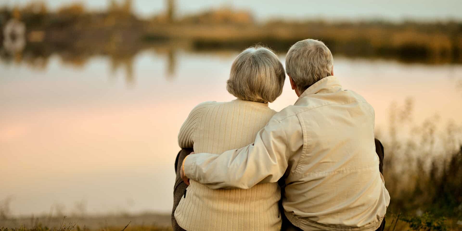 Happy,Senior,Couple,Sitting,In,Summer,Near,Lake,During,Sunset