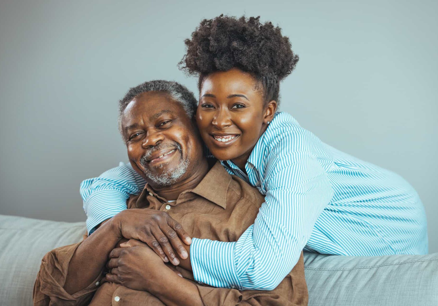 Smiling,Young,Woman,Sitting,On,Sofa,With,Happy,Older,Retired